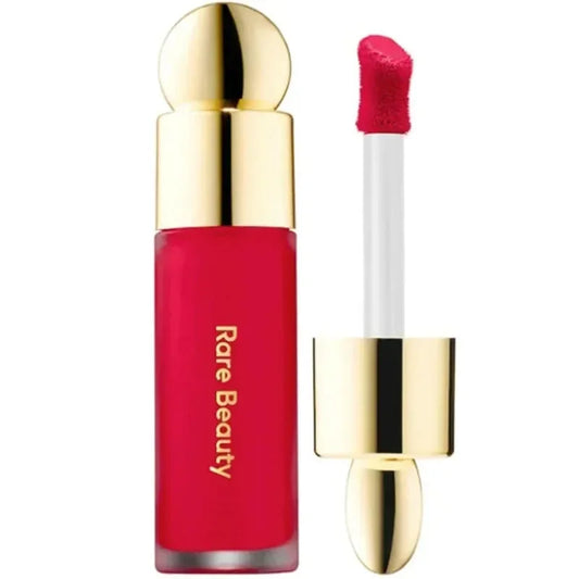 Labial líquido rojo con aplicador y tapa dorada, maquillaje Rare Beauty.