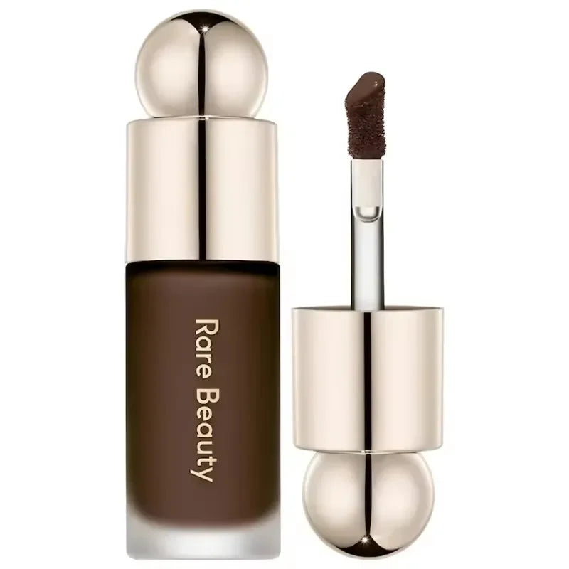 Corrector líquido marrón Rare Beauty con aplicador y envase dorado elegante de maquillaje