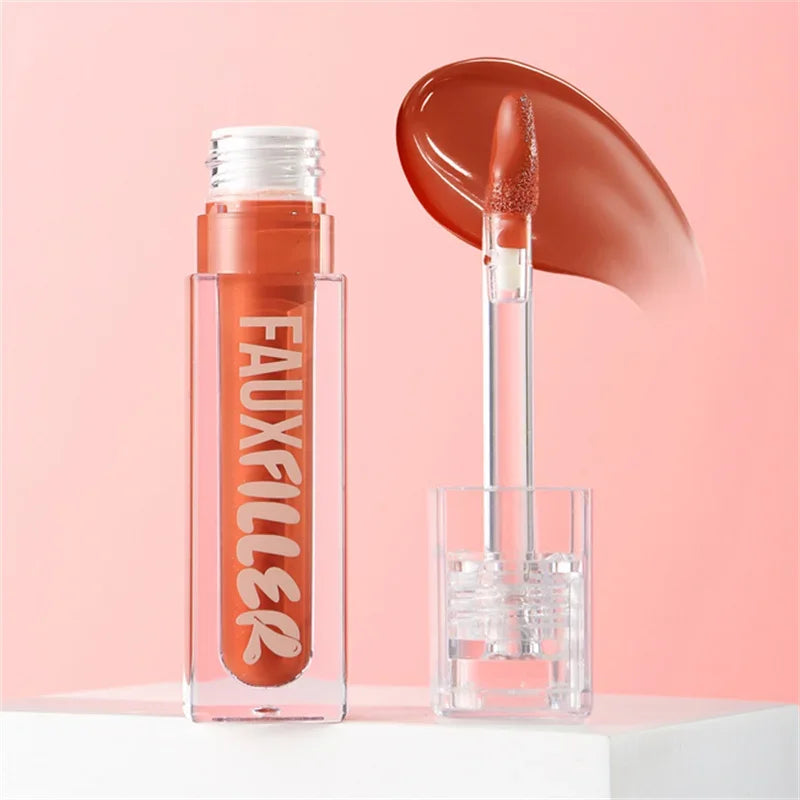 Brillo labial líquido tono marrón con aplicador y envase transparente sobre fondo rosa.