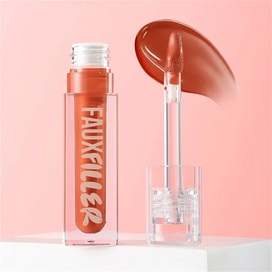Brillo labial líquido tono marrón con aplicador y envase transparente sobre fondo rosa.