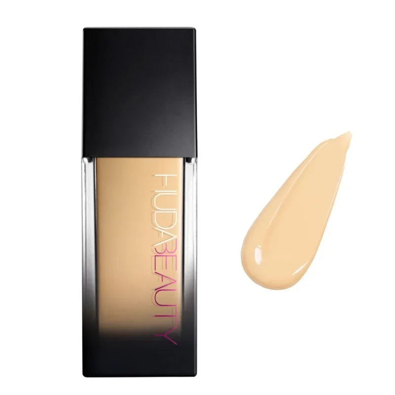 Base de maquillaje líquida tono beige con envase negro y muestra de color