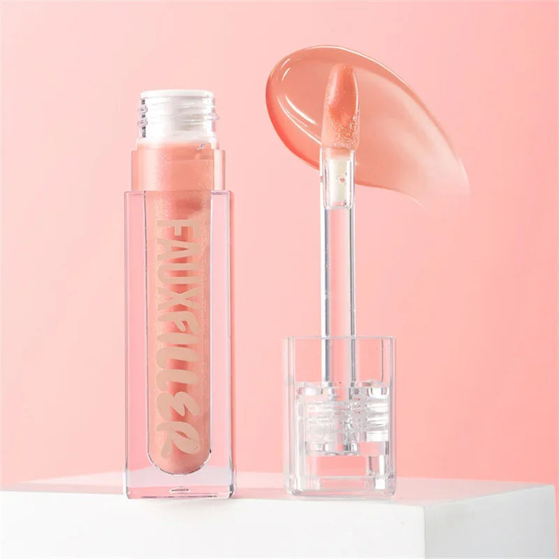 Brillo labial nude con aplicador, envase transparente sobre fondo rosa, maquillaje femenino.