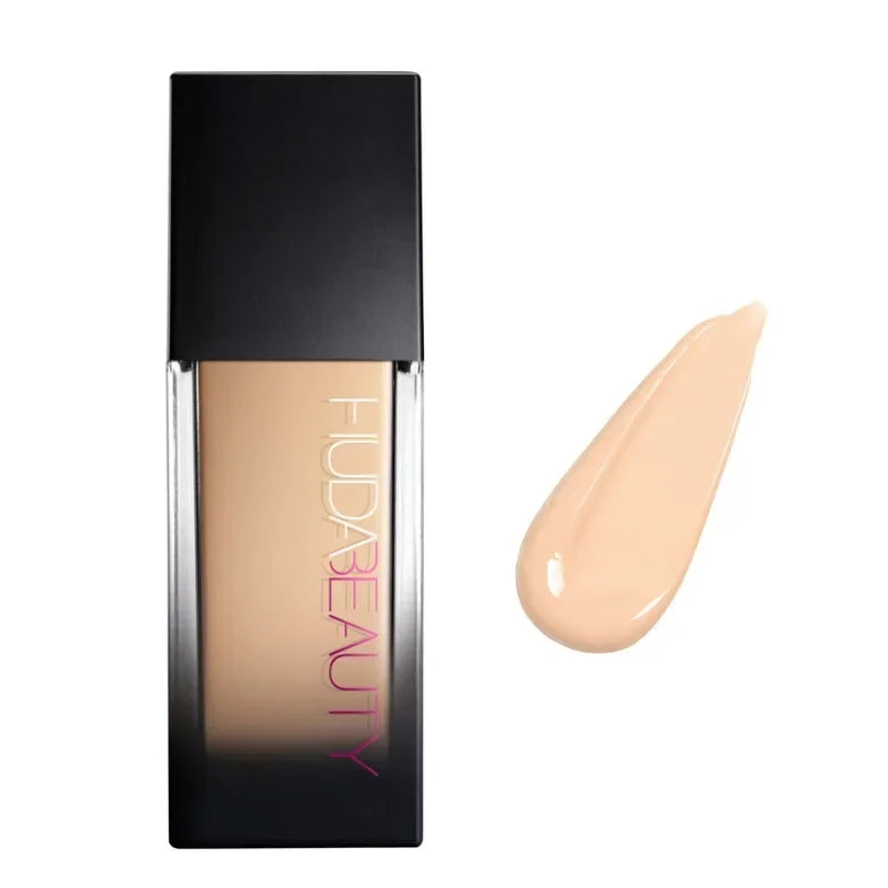 Base de maquillaje líquida tono claro con envase rectangular y muestra de color beige.